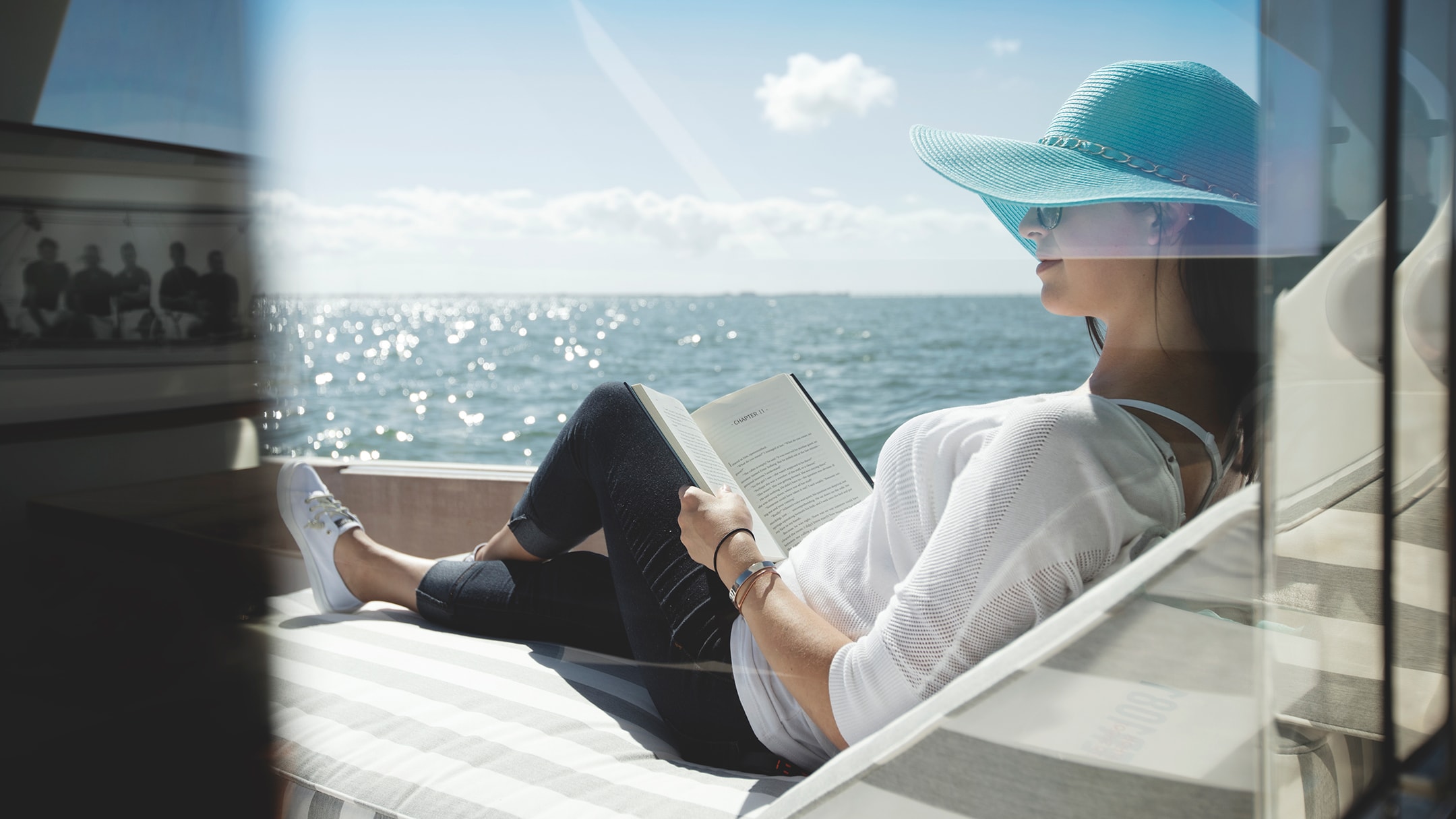 Woman relaxing in hat on back of boat in water