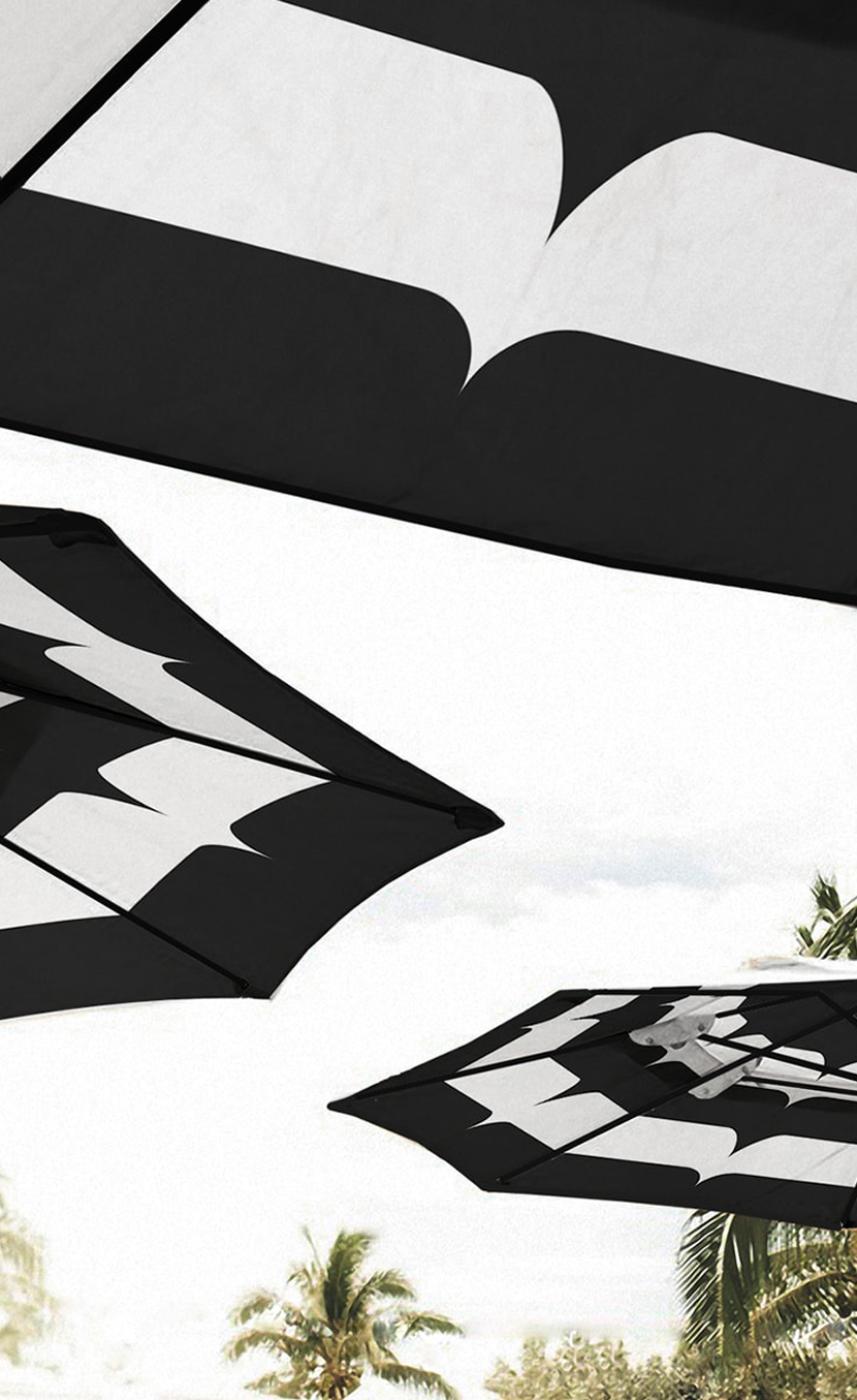 Black and white hotel pool umbrellas that feature a pattern from the Current's hotel branding.