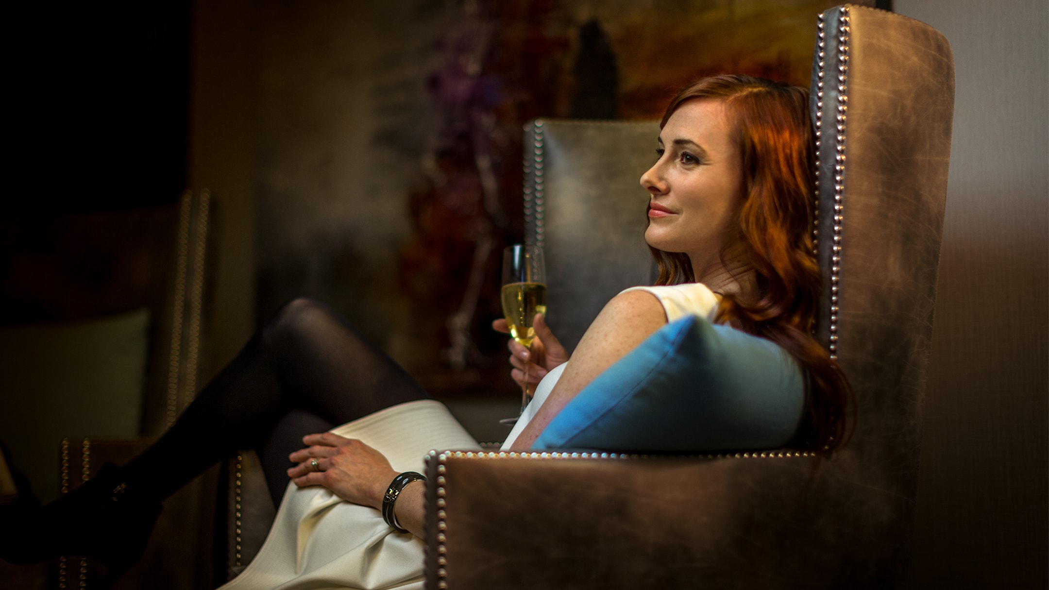 woman lounging in arm chair with champagne