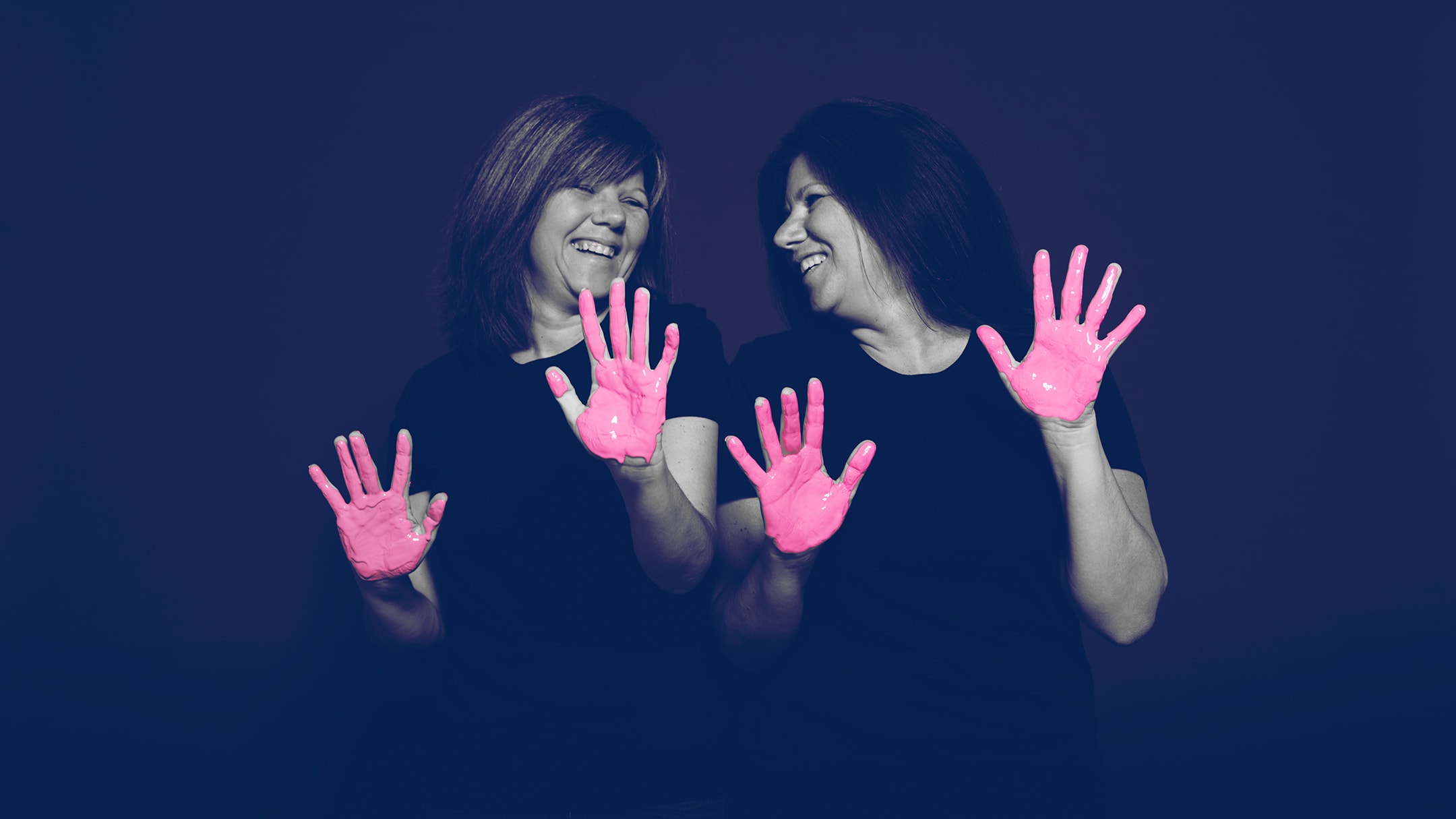Two breast cancer survivor posing for the in our hands hospital campaign with pink paint on her hands.