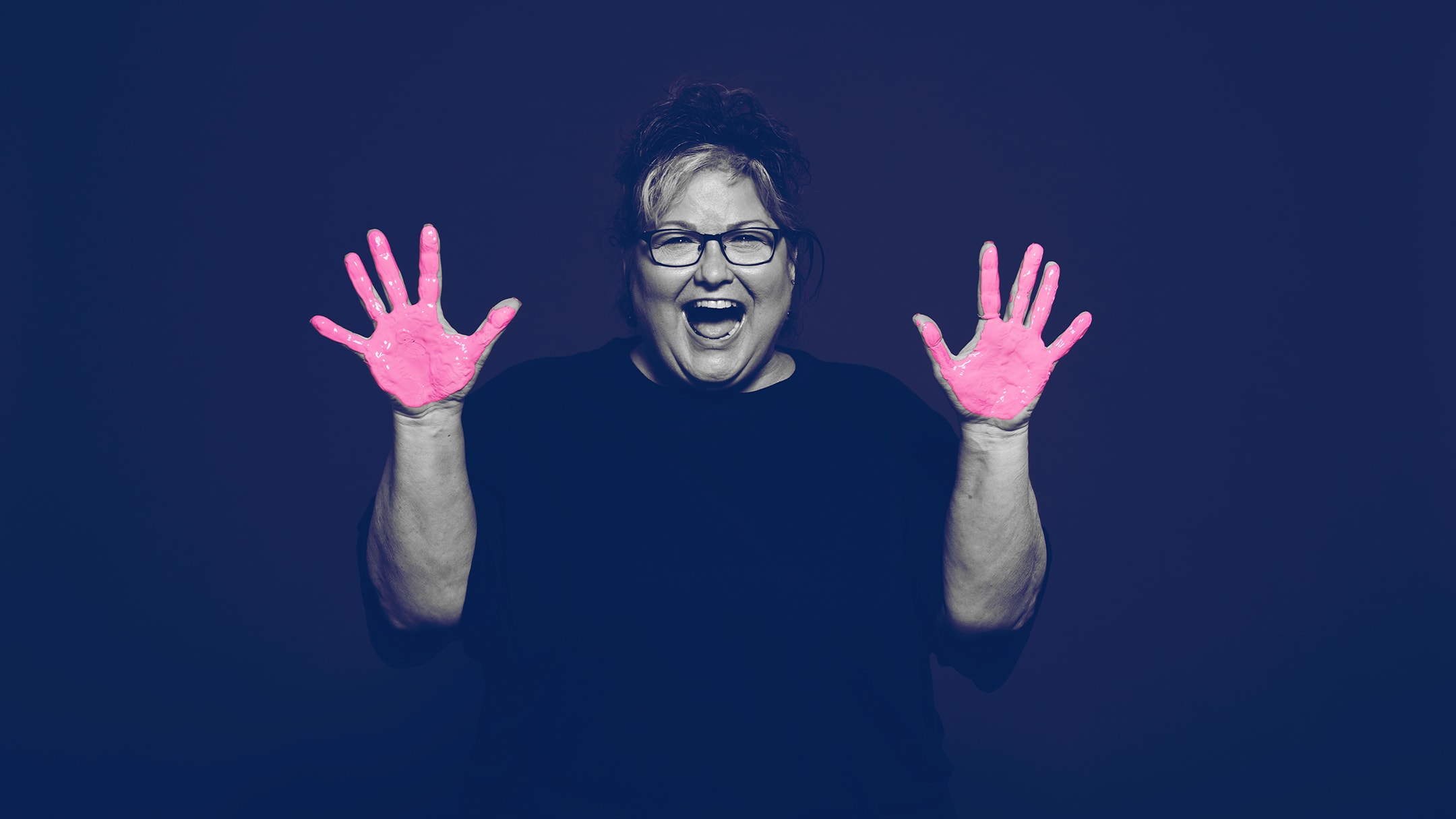 Breast cancer survivor posing for the in our hands campaign with pink paint on her hands