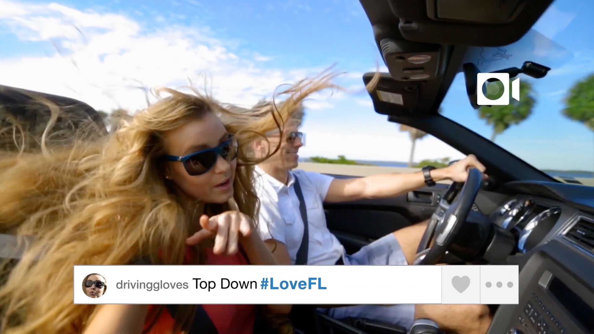 A screen grab of a woman's instagram post. She is the passenger in a top down convertible with her hair flying everywhere. The post says Top Down #LoveFL.
